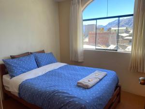 Schlafzimmer mit einem Bett mit blauer Bettwäsche und einem Fenster in der Unterkunft Homestay Pachamama in Cabanaconde