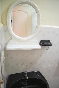 a bathroom with a mirror above a black toilet at Ima Sumaj Hostel in Copacabana