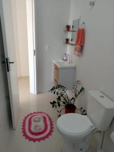 La salle de bains est pourvue de toilettes et d'un tapis rouge. dans l'établissement Apartamento Novo 500m da praia de Itajuba, à Barra Velha