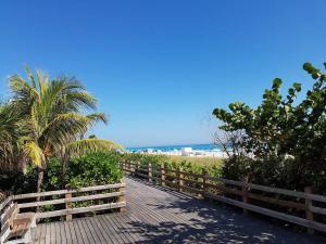 einen Fußweg zum Strand mit einem Zaun und Palmen in der Unterkunft Miami Beach Getaway 100 yards from Beach in Miami Beach