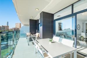 een appartement met een balkon met een witte tafel en stoelen bij Sunset Drive Resort Apartment 4-8 Poniente Beach in Benidorm