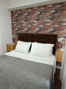 uma cama com almofadas brancas e uma parede de tijolos em Flat Wise SP em São Paulo