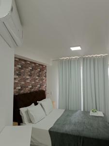 um quarto com uma cama grande e uma parede de tijolos em Flat Wise SP em São Paulo