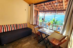 ein Wohnzimmer mit einem Sofa, einem Tisch und einem Fenster in der Unterkunft Suíte Sunset in Miguel Pereira