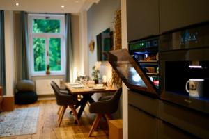a dining room with a table and a kitchen with a microwave at EDLER WOHNRAUM Luxuriöses Stadtstudio mit Einbaukaffeevollautomat, Balkon, Netflix & Klimaanlage in Zwickau