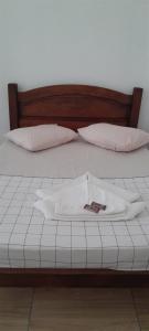 Una cama con sábanas blancas y almohadas. en Pousada Pé na Areia, en Paraty