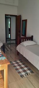 Pousada Pé na Areia في باراتي: غرفة نوم بسرير وارضية خشبية