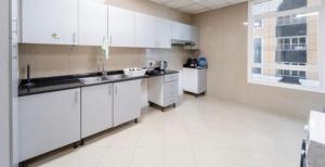 uma cozinha com armários brancos, um lavatório e um frigorífico em Greatest location Dubai em Dubai