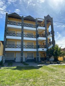 un edificio blanco y amarillo con un árbol delante en Complejo Berilde II en San Clemente del Tuyú