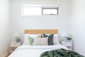 a bedroom with a white bed with pillows and a window at Elwood Star- Beachside Retreat in Melbourne