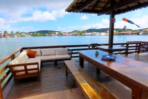 un ponte di legno con divano e tavoli su una barca di Casa Flora a Cabo Frio