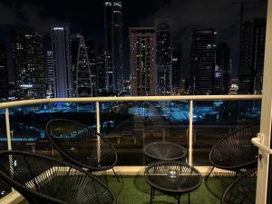 smilehomesdxb في دبي: شرفة مع كراسي وأفق المدينة في الليل