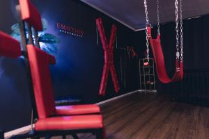 une chambre avec une chaise rouge et une balançoire dans l'établissement Erwachsenenhotel BDSM Apartment Hotel Emotion Apartments mit privater Sauna & Whirlpool, à Vlotho