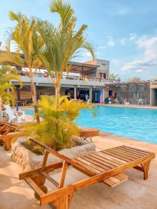 una piscina con bancos y palmeras junto a un complejo en La Rosa Náutica Club, en Guaduas