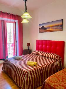 - une chambre avec un grand lit et une tête de lit rouge dans l'établissement Holiday House Ginevra, à Formia