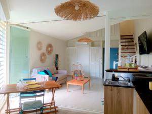 uma cozinha e sala de estar com uma mesa e um sofá em Blue Parasols - Suite Prestige Signature Relax mood em Le Diamant