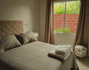 Bett in einem Zimmer mit Fenster und einem Bett mit Handtüchern in der Unterkunft Vina in Villa Elisa