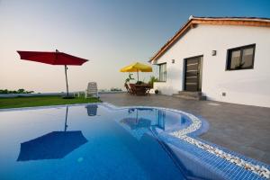 a swimming pool in front of a house with an umbrella at Casita Las Toscas in La Matanza de Acentejo