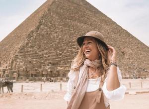 uma mulher está em pé em frente a uma pirâmide em Pyramids Hotel no Cairo
