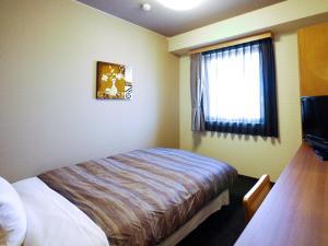 a hotel room with a bed and a window at Hotel Route-Inn Tajimi Inter in Tajimi