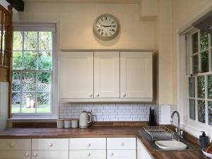 a kitchen with a clock on the wall above a counter at The Coach House at Pitchards in Halstead