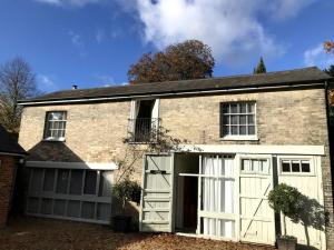 a brick house with a garage with white doors at The Coach House at Pitchards in Halstead