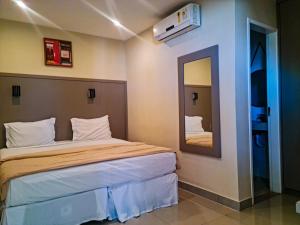 een hotelkamer met een bed en een spiegel bij Hotel Cravo e Canela in Campos dos Goytacazes