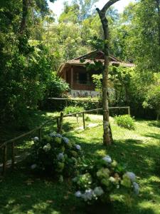 ein Haus inmitten eines Gartens mit einem Baum in der Unterkunft Pousada da Carmem in Visconde De Maua