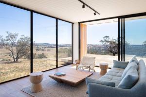 una sala de estar con grandes ventanas de cristal y un sofá. en Spectacular Kangaroobie Cabin en Borenore