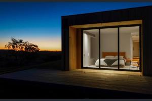 1 dormitorio con vistas a una cama a través de una ventana en Spectacular Kangaroobie Cabin en Borenore