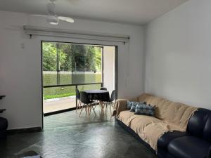 ein Wohnzimmer mit einem Sofa und einem Tisch in der Unterkunft Condomínio Buritis Centro de Bertioga a 100Mts da praia in Bertioga