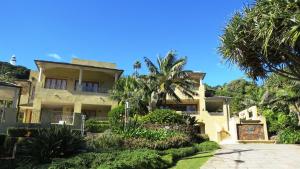 a house with palm trees in front of it at Victoria's At Wategos in Byron Bay