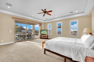 a bedroom with a bed and a tv and a balcony at Oasis Retreat at Henderson Greens in Las Vegas