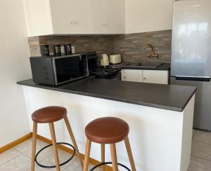 kuchnia z 2 stołkami barowymi i kuchenką mikrofalową w obiekcie Top Floor Executive apartment w Kapsztadzie