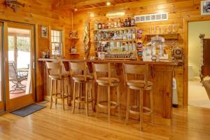 a bar in a cabin with wooden walls and wooden stools at Riverfront Luther Cottage with Year-Round Trail! in Luther