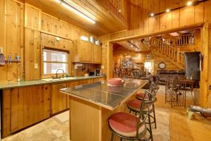 a kitchen with wooden walls and a large island with bar stools at Riverfront Luther Cottage with Year-Round Trail! in Luther