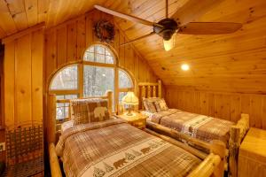 a log cabin bedroom with two beds and a ceiling fan at Riverfront Luther Cottage with Year-Round Trail! in Luther