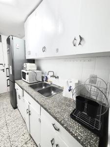 a kitchen with white cabinets and a sink and a microwave at Hermoso, amplio y nuevo departamento, en la mejor ubicacion de la ciudad de Mendoza in Mendoza