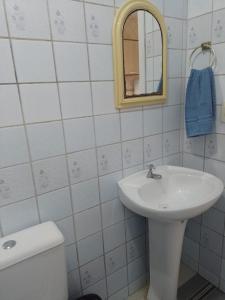 a bathroom with a sink and a mirror and a toilet at Reencanto Sonho Azul in Palhoça