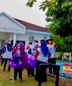a group of people standing in a yard with purple balloons at PD Best Homestay in Port Dickson
