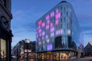 倫敦的住宿－W London，一座高大的玻璃建筑,上面有紫色的灯