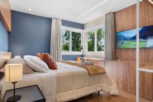 een slaapkamer met een groot bed en een televisie bij Toscano Cabernet 2 Suítes by Achei Gramado in Gramado