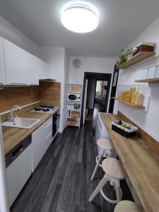 una cocina con armarios blancos y una barra con taburetes en Prievidza Home, en Prievidza