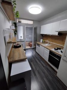 cocina con armarios blancos y encimera de madera en Prievidza Home, en Prievidza
