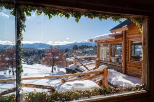 una ventana con vistas a una cabaña en la nieve en Pueblo Alto Lodge en Lago Futalaufquen