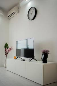 a television on a white cabinet with a clock on the wall at Quiet Apartment Ruby Horizon in Bucharest