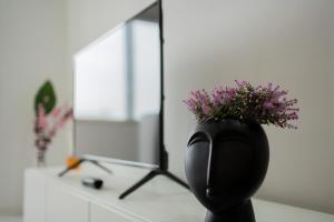 a black vase with flowers on a counter in front of a mirror at Quiet Apartment Ruby Horizon in Bucharest