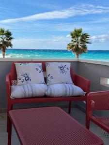 a red couch sitting on a balcony with the ocean at AD in Capo dʼOrlando