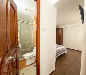 a bathroom with a toilet and a shower and a bed at Varvel residence in Cusco