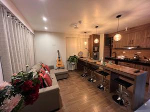 a living room with a couch and a table and a kitchen at Varvel residence in Cusco